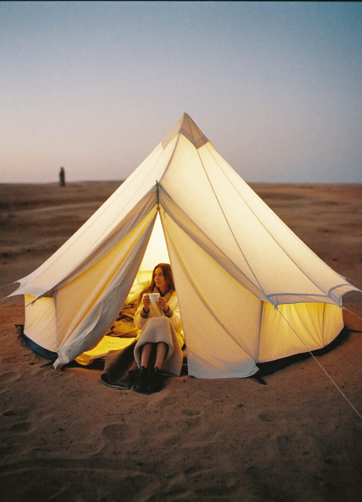 A lit tent on a dune at blue hour
