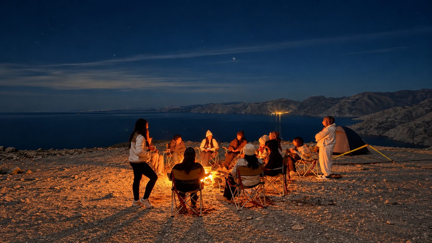 Women gathered around a campfire by the sea at night