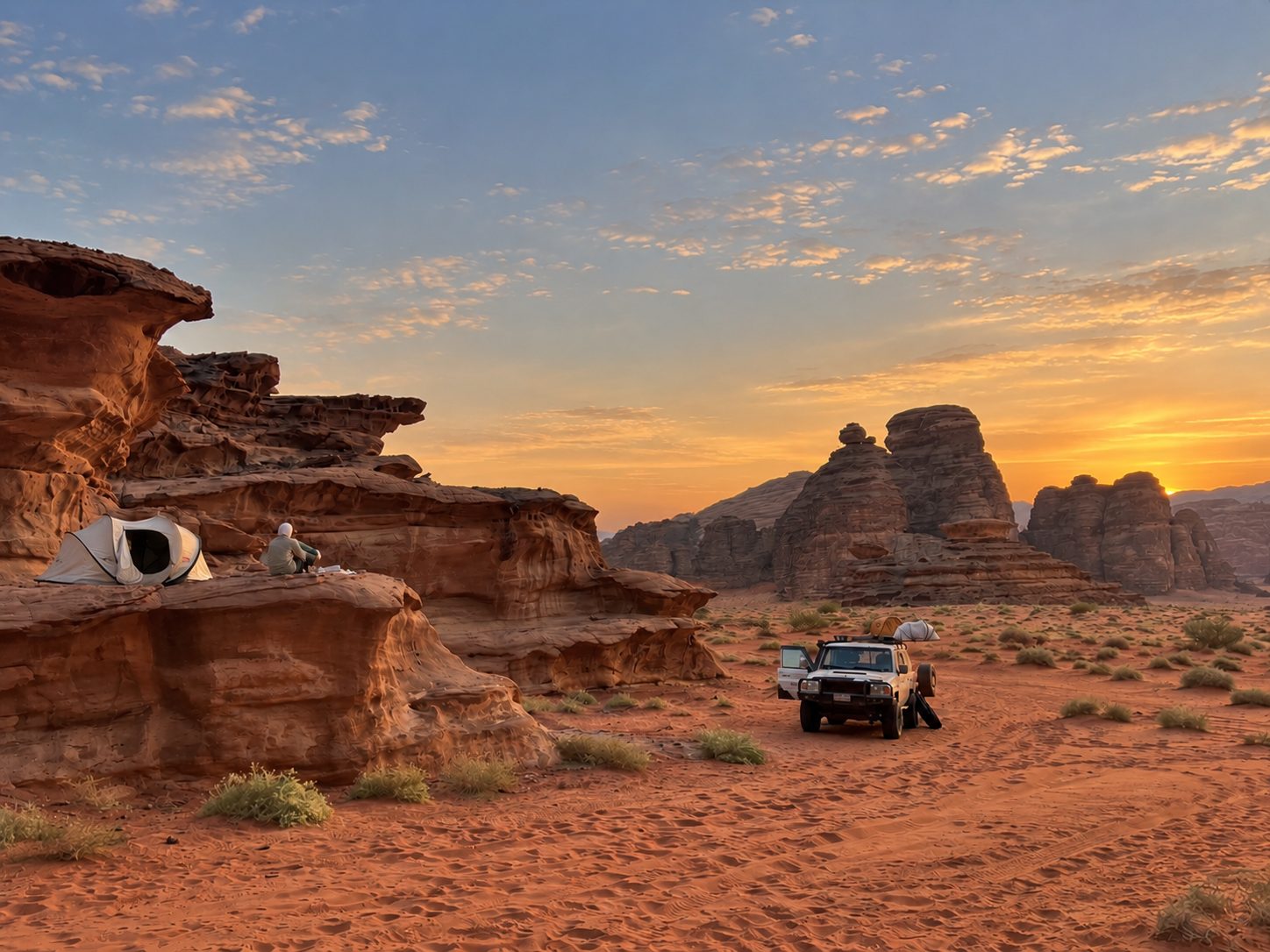 A desert camp among red rock formations at sunset