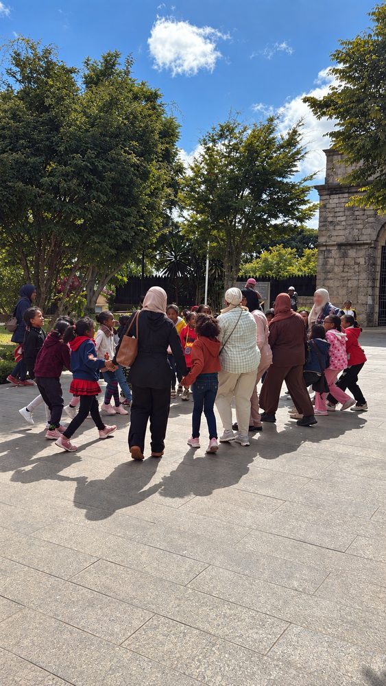 Women playing a circle game with children in a town square
